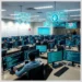 A large training room with rows of monitors showing code and people working together to practice ctf labs auditors practice skills.