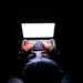 Person in a hoodie typing on a laptop in the dark illustrating ModularDS vs iThemes Security: Which One Will Protect Your Site?