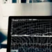 Close-up of a dark monitor displaying multiple line charts, grids, and performance indicators suggesting uptime and metrics comparison: ModularDS vs UptimeRobot: Discover the Ultimate Monitoring Showdown!